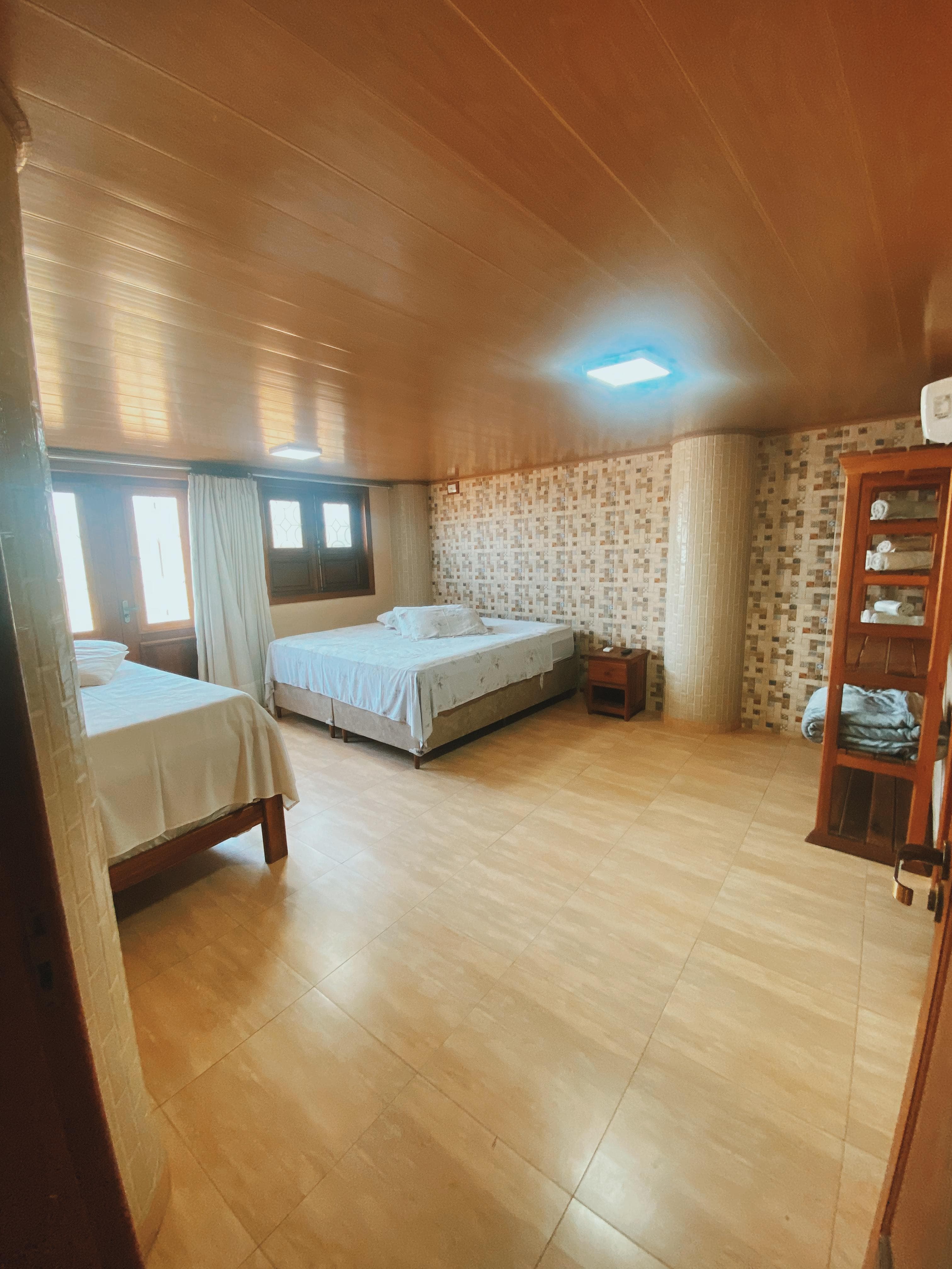 Suíte da pousada com camas, ar-condicionado e acabamentos em madeira